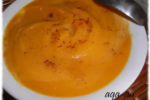 Aksamitna zupa z batatów, doprawiona szafranem i cynamonem, podana w białej miseczce z łyżką.
