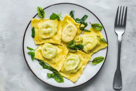 Pyszne ravioli z zielonym nadzieniem, udekorowane listkami. Idealny przepis na obiad.