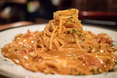 Pyszne spaghetti burrata w kremowym sosie, posypane zieloną pietruszką, czeka na spróbowanie.