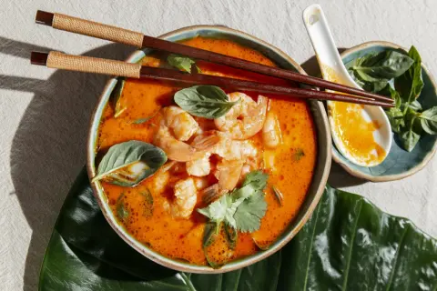 Aksamitny, pomarańczowy bulion z krewetkami i ziołami. Aromatyczny tom yam gotowy do spożycia pałeczkami.