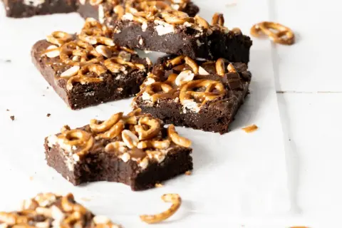 Czekoladowe brownie z karmelem i orzechami, posypane kawałkami precelków. Pyszna przekąska.