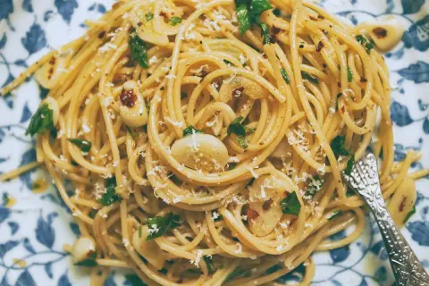 Pyszne spaghetti aglio olio z czosnkiem, natką pietruszki i płatkami chili, posypane parmezanem.