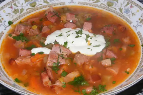 Zupa solanka z kawałkami mięsa, warzywami i śmietaną, posypana natką pietruszki. Pyszne danie na chłodne dni.