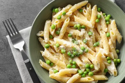 Penne z kremowym sosem i zielonym groszkiem, posypane parmezanem. Idealne danie, gdy masz ochotę na pyszny makaron z groszkiem.