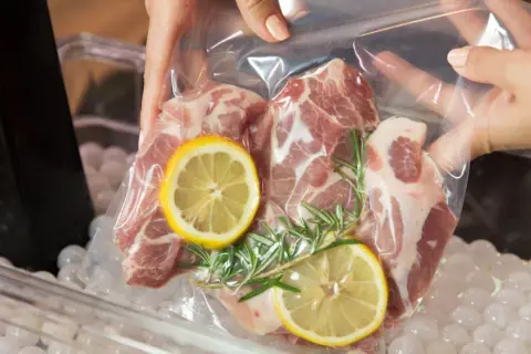 Mięso wieprzowe z cytryną i rozmarynem w woreczku do metody sous vide, gotowe do kąpieli wodnej.