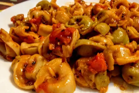 Pyszne tortellini z pomidorami i mozzarellą w sosie, danie gotowe do podania.