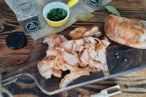 Pokrojone, przyprawione mięso na kebaba leży na drewnianej desce obok przypraw i ziół.