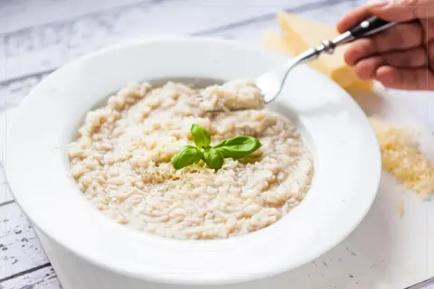 Kremowe risotto bianco z parmezanem i bazylią, gotowe do zjedzenia.