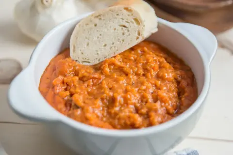 Gęsta, aromatyczna toskańska zupa pomidorowa z kawałkiem chleba, podana w białej miseczce.