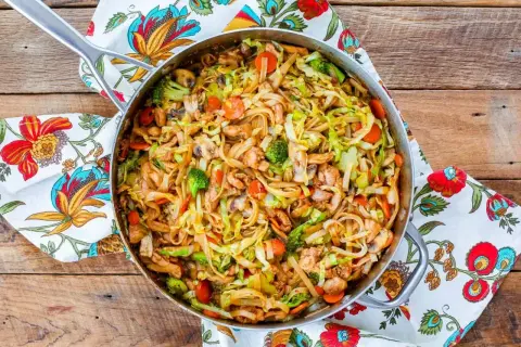 Smażony makaron z kurczakiem i warzywami: brokuły, marchewka, kapusta i pieczarki w sosie. Pyszne danie w woku.