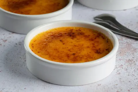 Dwa białe naczynia z pyszną, skarmelizowaną górą, idealne na deser crema catalana.