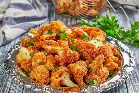 Chrupiące warzywa w panko, podane na ozdobnej tacy, posypane natką pietruszki. Idealna przekąska!