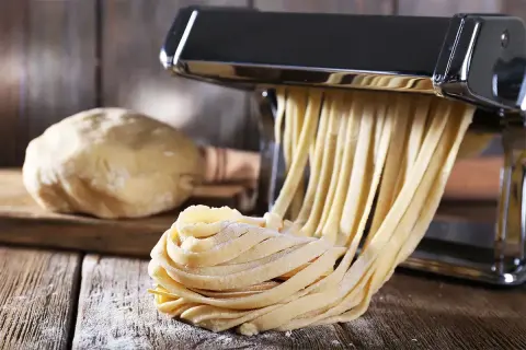 Maszyna do makaronu tworzy świeże tagliatelle z ciasta. Idealny sposób, jak zrobić makaron w domu.