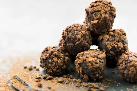 Stos pysznych, czekoladowych kulek Ferrero Rocher, posypanych kakao, kusi swoim wyglądem.
