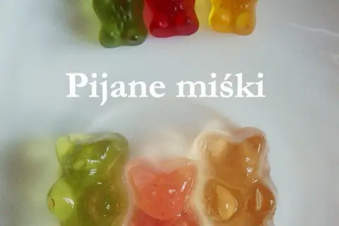 Kolorowe żelki z alkoholem w kształcie misiów, niektóre lekko rozpuszczone, tworzą słodką i odurzającą kompozycję.