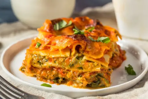Pyszna lasagne wegetariańska z warzywami i sosem pomidorowym, udekorowana świeżą bazylią.