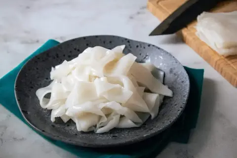 Płaski, biały makaron ryżowy na talerzu, gotowy do przygotowania pysznych dań. Szukasz inspiracji? Sprawdź makaron vermicelli przepisy!