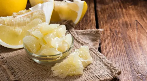 Soczyste kawałki pomelo w miseczce i obok, pokazujące, jak jeść ten owoc.