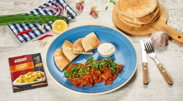 Pyszne wołowina po indyjsku z pitą i dipem. Obok przyprawa curry, czosnek, cytryna i chili.