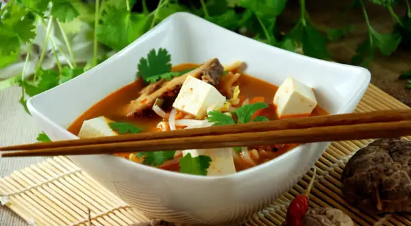 Aksamitna zupa koreańska z kostkami tofu, kiełkami i świeżą kolendrą, gotowa do spożycia pałeczkami.