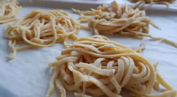 Świeże, domowe tagliatelle uformowane w gniazda. Zastanawiasz się, ile jajek do makaronu? Te wyglądają na idealne!