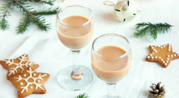 Dwa kieliszki z kremowym likierem nutella, ozdobione świątecznymi pierniczkami i gałązkami świerku.