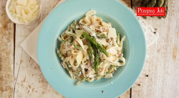Tagliatelle ze szparagami w kremowym sosie, posypane parmezanem. Pyszne danie na wiosnę.