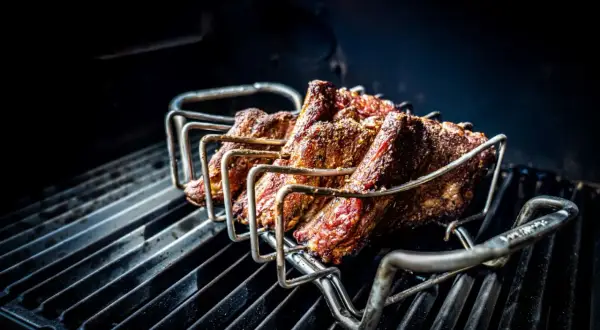 Żeberka w stojaku na grillu, gotowe na prawdziwy barbecue po polsku. Soczyste mięso pieczone na ruszcie.