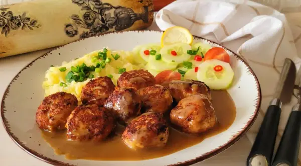 Pyszne pulpety szwedzkie w sosie, podane z puree ziemniaczanym i sałatką z ogórka.