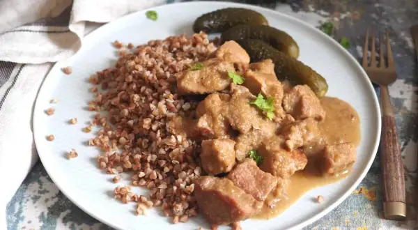Pyszny gulasz z szynki podany z kaszą gryczaną i ogórkami kiszonymi. Aromatyczne danie, które zachwyci każdego smakosza.