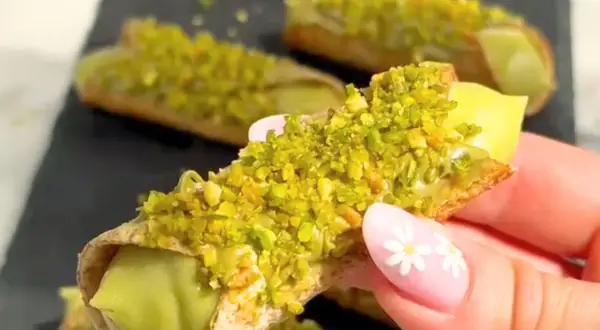 Chrupiące rurki wypełnione kremowym nadzieniem, obficie posypane zielonymi, aromatycznymi pistacjami. Te cannoli pistacjowe wyglądają niezwykle apetycznie.