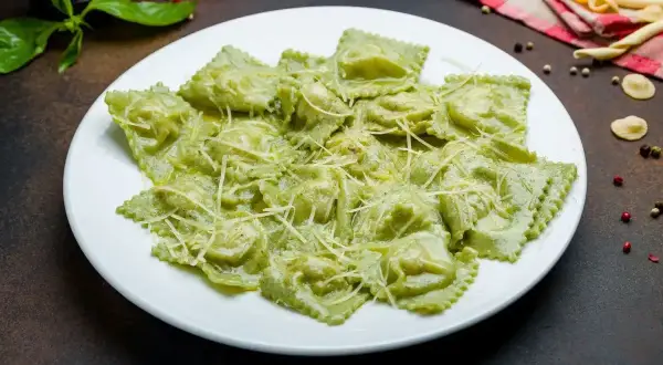 Pyszne ravioli ze szpinakiem i ricottą, polane kremowym sosem i posypane parmezanem. Idealne na lekki obiad.