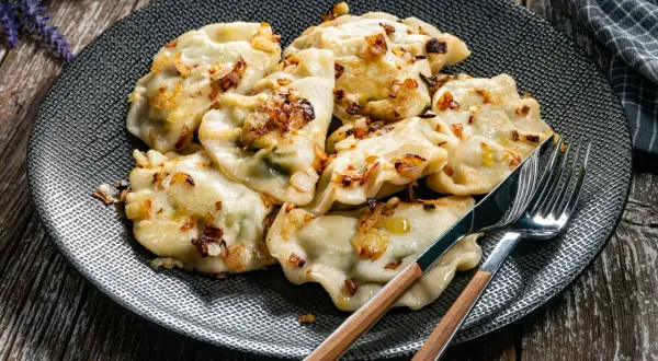 Pyszne pierogi z cebulką na talerzu. Czy pierogi gotować pod przykryciem? To pytanie zadaje sobie wielu kucharzy.