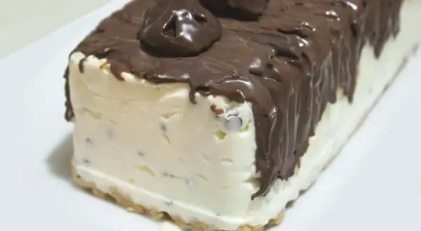 Pyszne lody sernikowe w kształcie bloku, oblane czekoladą z kawałkami czekolady na wierzchu.