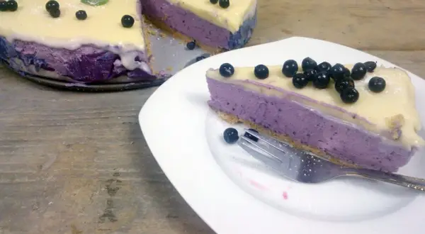 Pyszny sernik jagodowy na zimno z mascarpone, udekorowany świeżymi borówkami i listkami mięty. Idealny deser na letnie dni.