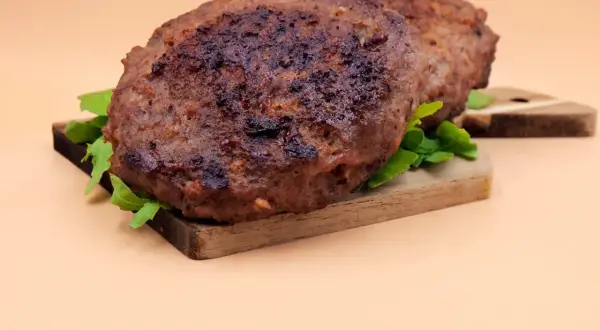 Dwa soczyste kotlety na desce, idealne do burgera. Dowiedz się, jak smażyć burgera, by były tak pyszne!
