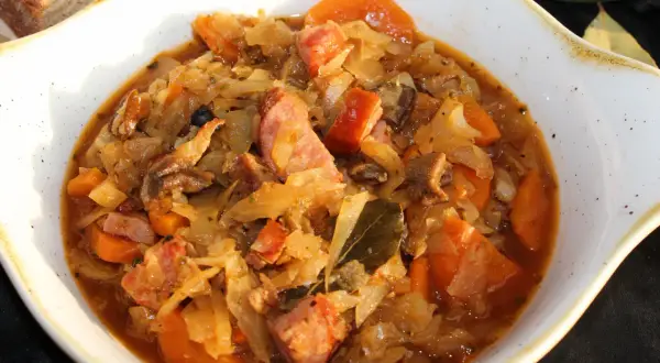 Bigos ze słodkiej kapusty Ani gotuje się powoli, by wydobyć głębię smaku. Widać kawałki kiełbasy, marchewki i liście laurowe.