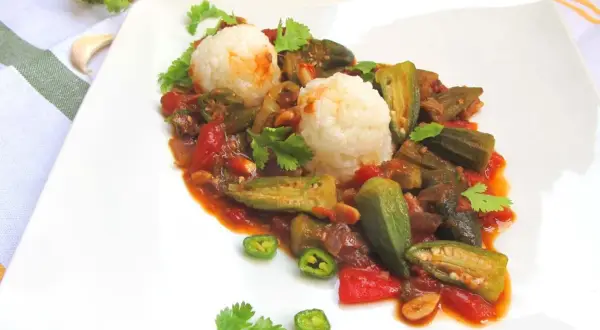 Pyszne okra przepisy na talerzu: duszona okra z pomidorami i ryżem, ozdobione kolendrą i papryczką chili.