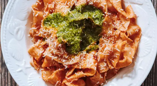Pappardelle all'arrabbiata przepis: szeroki makaron z pikantnym sosem pomidorowym, zielonym pesto i parmezanem.
