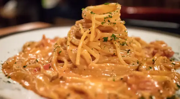Pyszne spaghetti burrata w kremowym sosie, posypane zieloną pietruszką, czeka na spróbowanie.