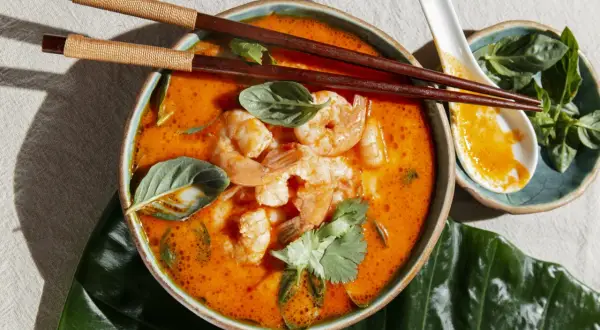 Aksamitny, pomarańczowy bulion z krewetkami i ziołami. Aromatyczny tom yam gotowy do spożycia pałeczkami.
