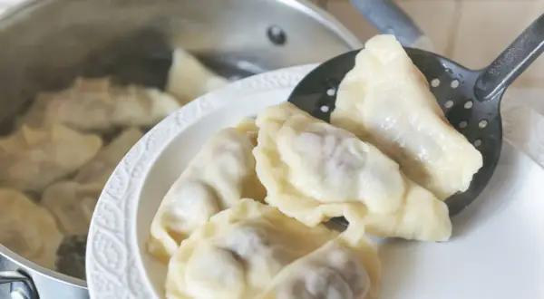 Gorące pierogi wyjmowane łyżką cedzakową z garnka. Czy pierogi przelewa się zimną wodą? Nie, gorące prosto z wody na talerz.