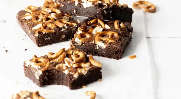 Czekoladowe brownie z karmelem i orzechami, posypane kawałkami precelków. Pyszna przekąska.