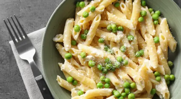 Penne z kremowym sosem i zielonym groszkiem, posypane parmezanem. Idealne danie, gdy masz ochotę na pyszny makaron z groszkiem.