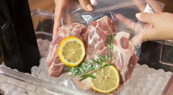 Mięso wieprzowe z cytryną i rozmarynem w woreczku do metody sous vide, gotowe do kąpieli wodnej.