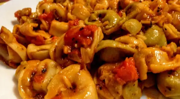 Pyszne tortellini z pomidorami i mozzarellą w sosie, danie gotowe do podania.