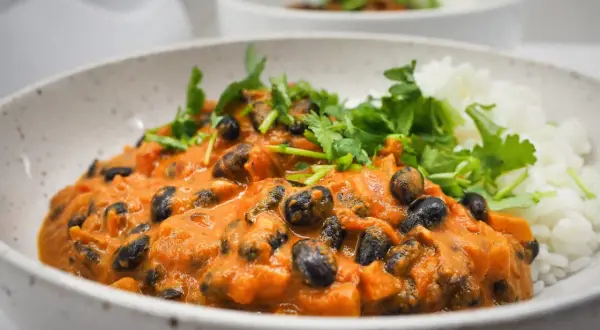 Pyszna fasola masala w kremowym sosie pomidorowym, podana z ryżem i świeżą kolendrą.