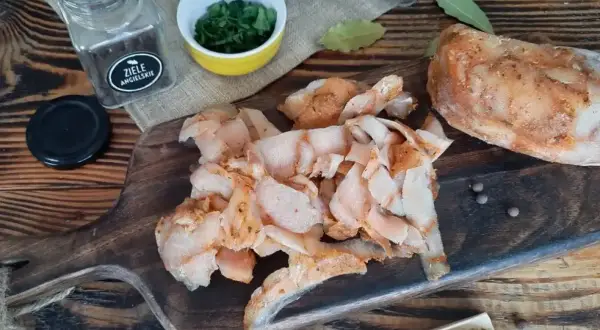 Pokrojone, przyprawione mięso na kebaba leży na drewnianej desce obok przypraw i ziół.