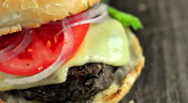 Pyszne burgery z czarnej fasoli z serem, pomidorem i czerwoną cebulą, podane w miękkiej bułce.