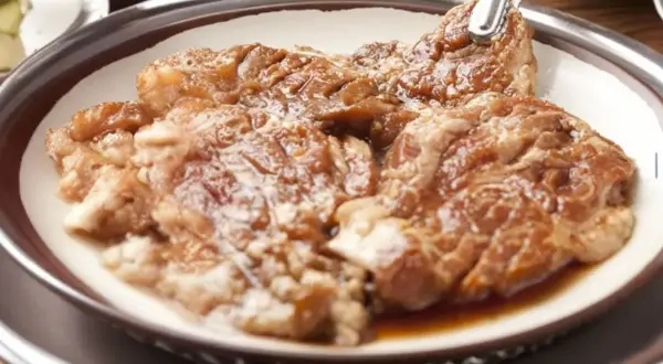 Soczyste skrzydełka w miodzie, gotowe do grillowania. Mięso jest błyszczące od marynaty, zapowiada się pyszny posiłek.